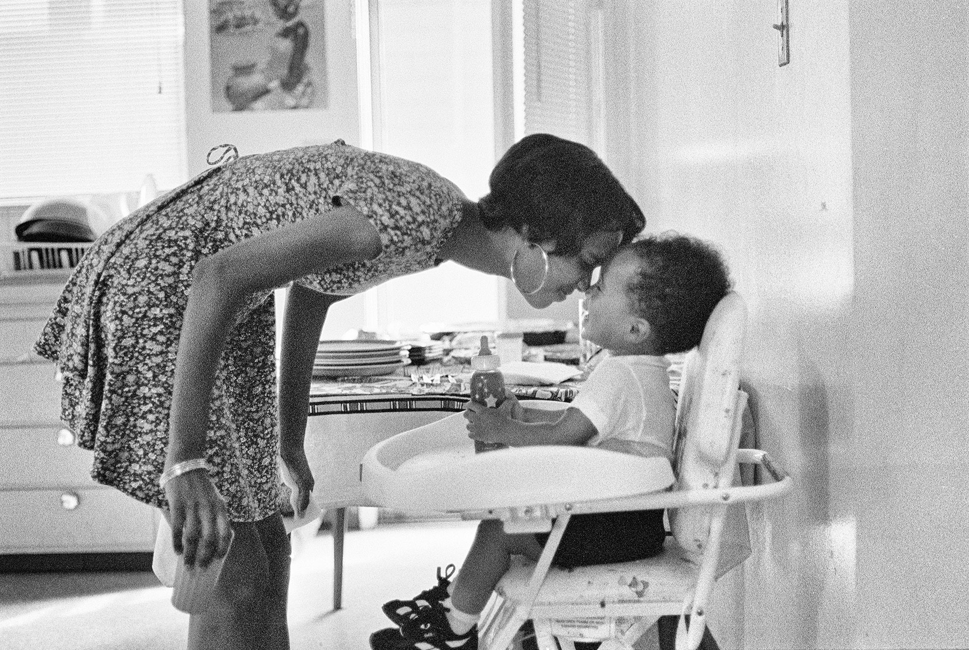 A mother rubs noses with her infant son in a high chair in Oakland, California, in 1994.