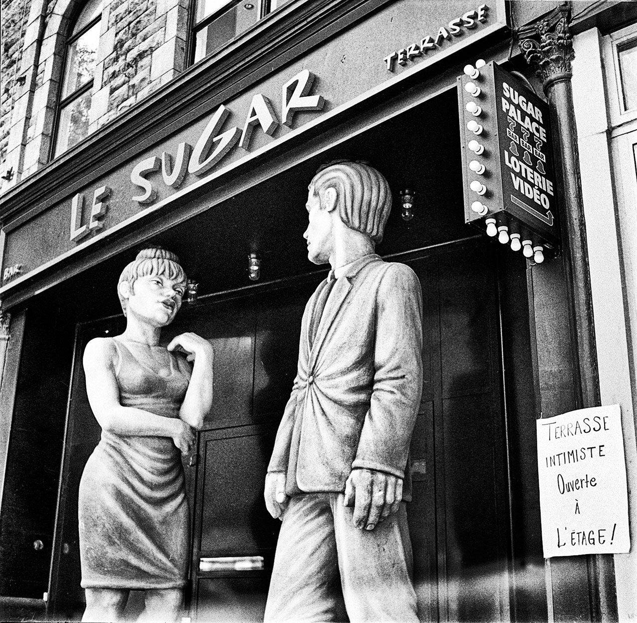 A pair of male and female mannequins pose outside a Montreal bar, 2000.