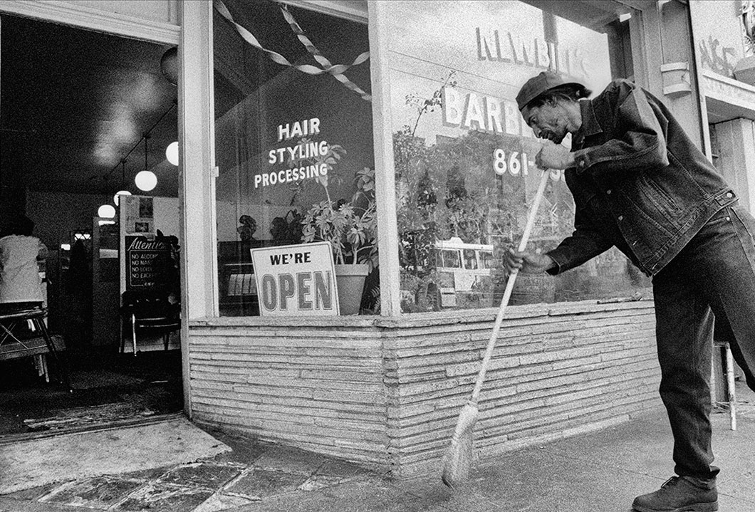A barber is sweeping the sidewalk in front of his San Francisco shop, 1994.