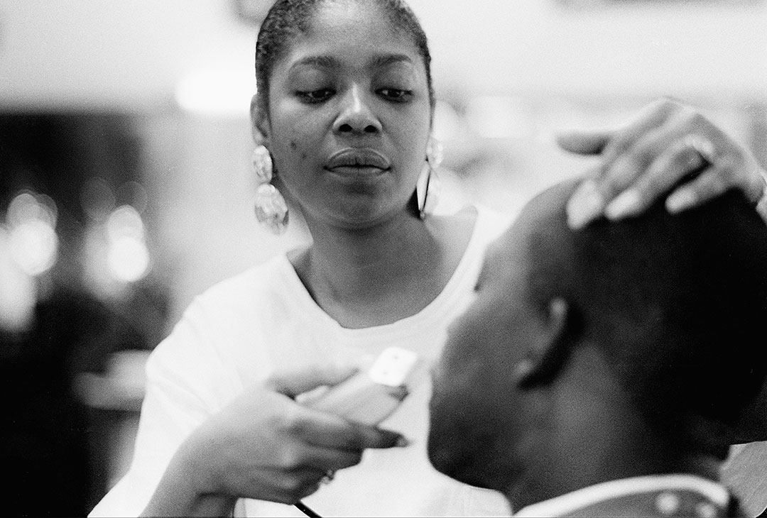 A woman barber trims a customer's moustache; San Francisco, 1994