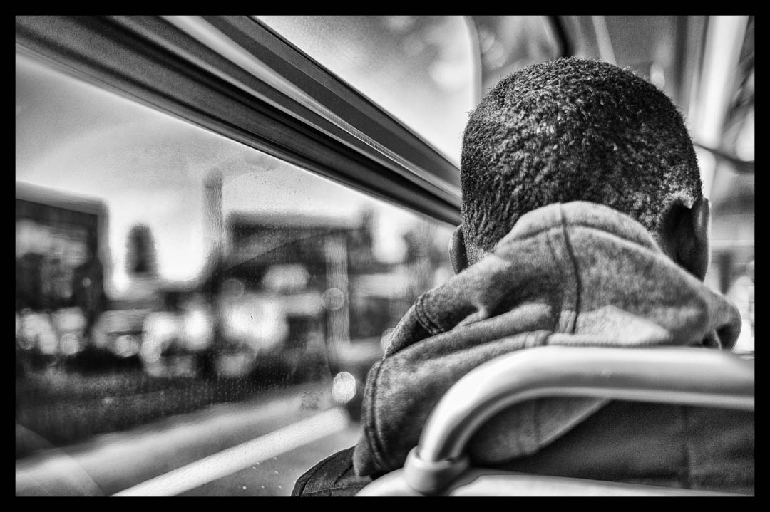 A Black man sits alone on a city bus in Oakland, California in 2017.